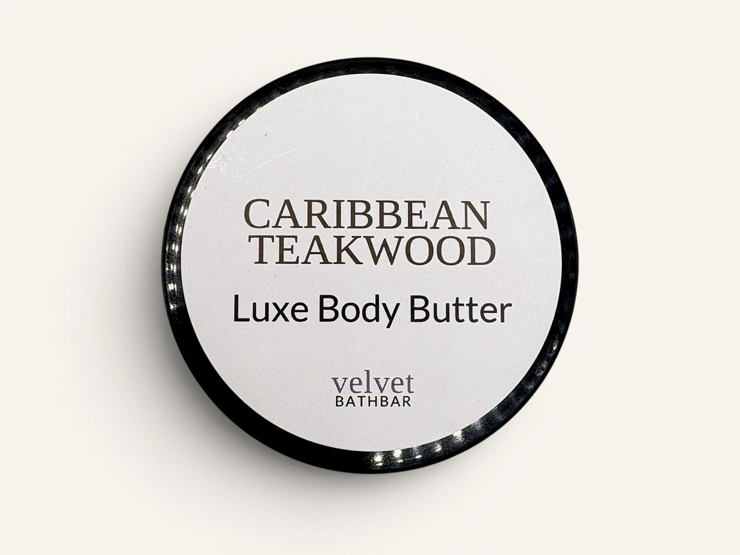 Velvet Bath Bar Caribbean Teakwood Luxe Body Butter in a black jar with a white label.