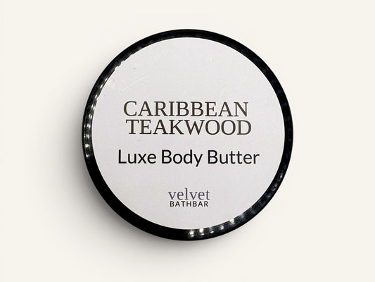 Velvet Bath Bar Caribbean Teakwood Luxe Body Butter in a black jar with a white label.